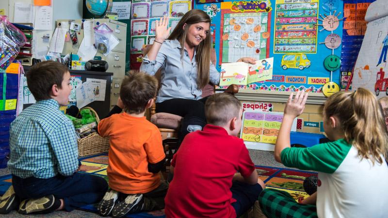 Education student reading book to elementary school children